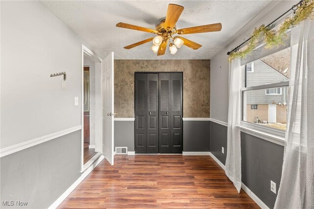 interior space featuring visible vents, ceiling fan, a textured ceiling, wood finished floors, and baseboards