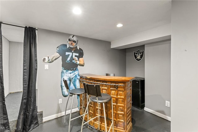 bar with baseboards, a bar, finished concrete flooring, and recessed lighting