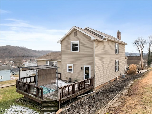 rear view of property with a chimney and a deck