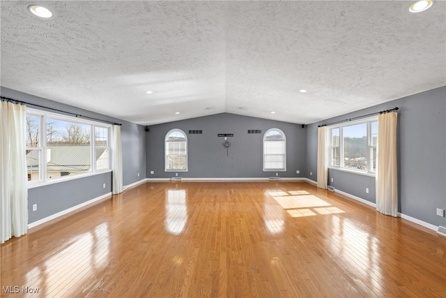 unfurnished living room featuring a healthy amount of sunlight, baseboards, vaulted ceiling, and wood finished floors