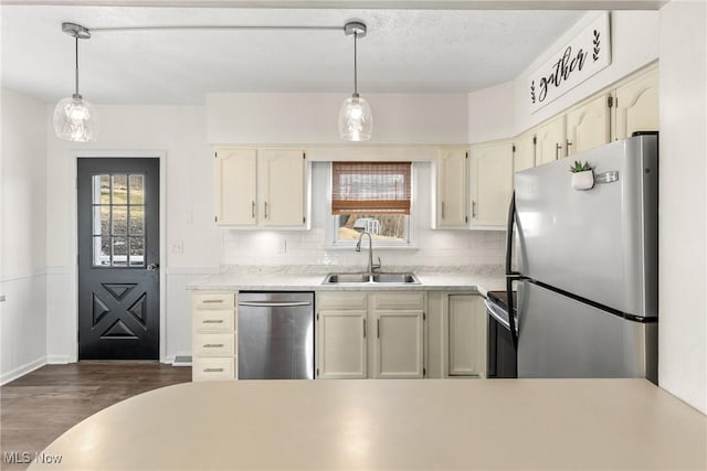 kitchen featuring light countertops, appliances with stainless steel finishes, a sink, and pendant lighting