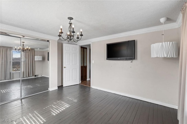 unfurnished living room featuring dark wood-style floors, crown molding, a textured ceiling, and a notable chandelier