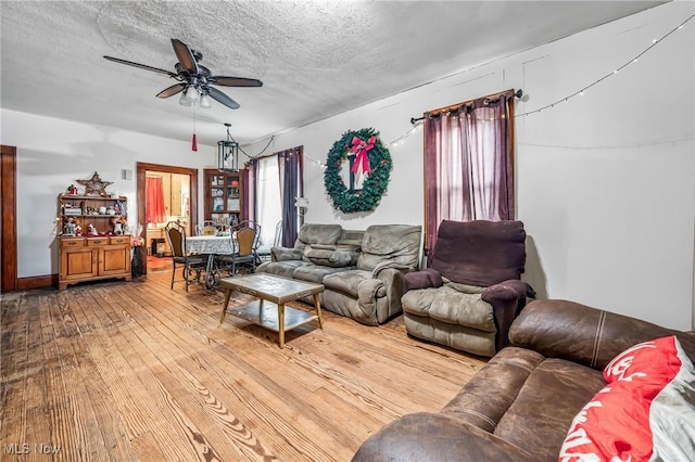 living room with ceiling fan, wood-type flooring, and a textured ceiling