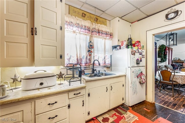 kitchen with a paneled ceiling, white fridge, and sink