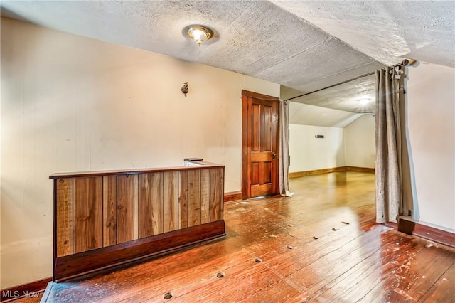 bonus room featuring hardwood / wood-style floors, a textured ceiling, and vaulted ceiling