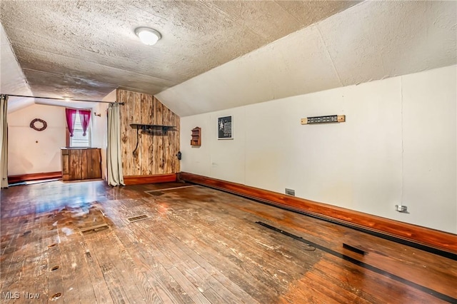 bonus room featuring a textured ceiling, hardwood / wood-style floors, and vaulted ceiling