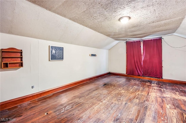 bonus room with a textured ceiling, dark wood-type flooring, and vaulted ceiling