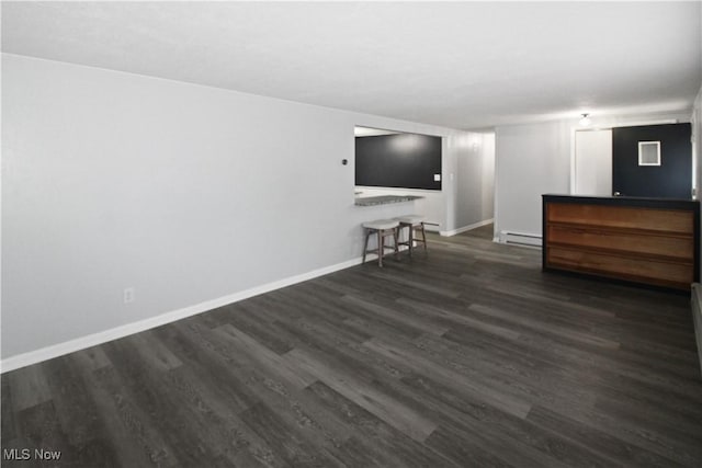 unfurnished living room featuring dark hardwood / wood-style flooring and a baseboard radiator