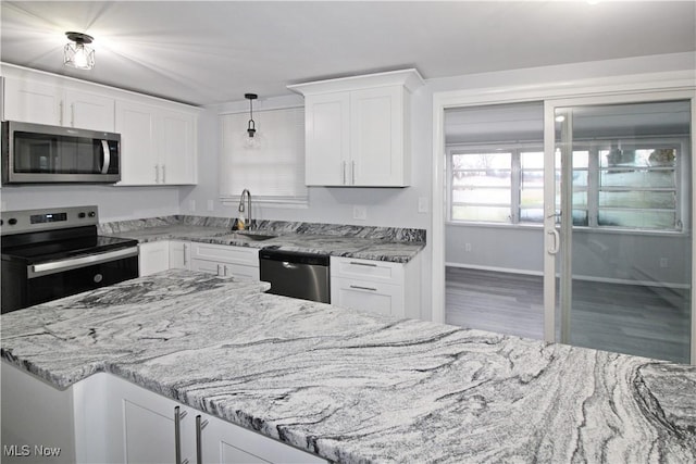 kitchen featuring pendant lighting, white cabinets, sink, appliances with stainless steel finishes, and light stone counters