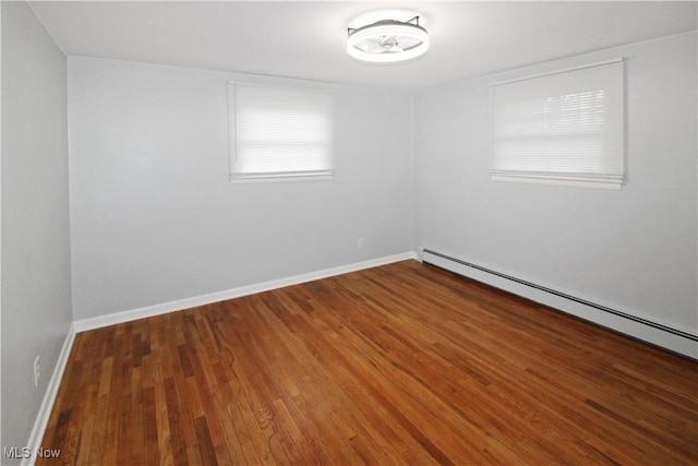 unfurnished room with dark hardwood / wood-style flooring and a baseboard heating unit