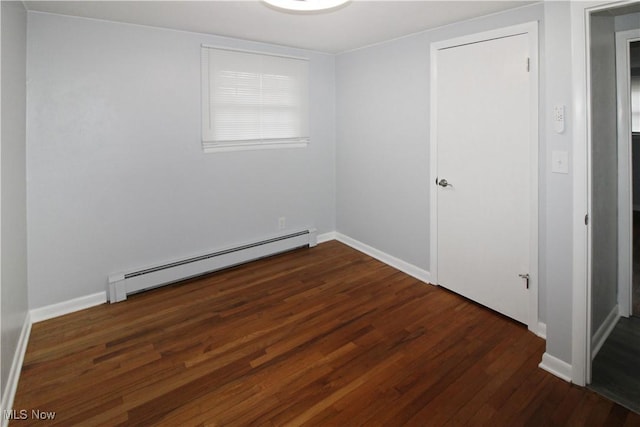 spare room with baseboard heating and dark wood-type flooring