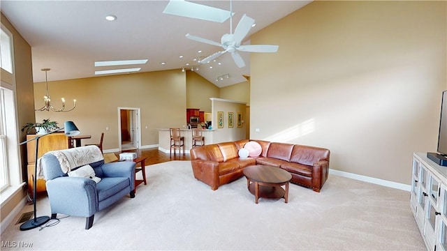 carpeted living room featuring ceiling fan with notable chandelier and vaulted ceiling with skylight