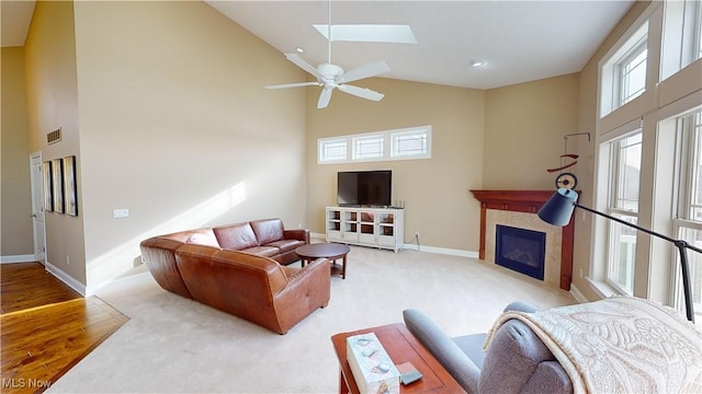 living room featuring a fireplace, a high ceiling, a skylight, and a healthy amount of sunlight