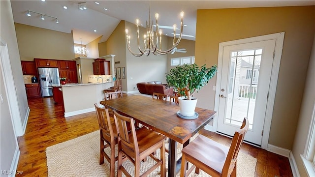 dining area with a notable chandelier, dark wood-type flooring, and high vaulted ceiling