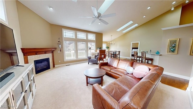 carpeted living room with ceiling fan with notable chandelier, a towering ceiling, and a tile fireplace