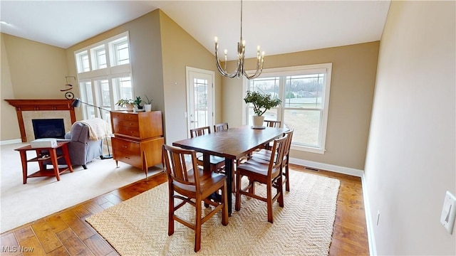 dining area with vaulted ceiling, wood-type flooring, and an inviting chandelier