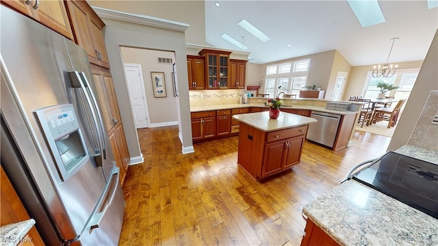 kitchen with kitchen peninsula, appliances with stainless steel finishes, backsplash, a center island, and hanging light fixtures