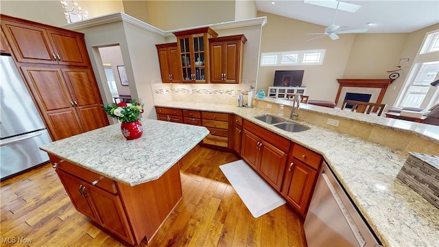 kitchen with a skylight, light stone countertops, sink, stainless steel appliances, and decorative backsplash