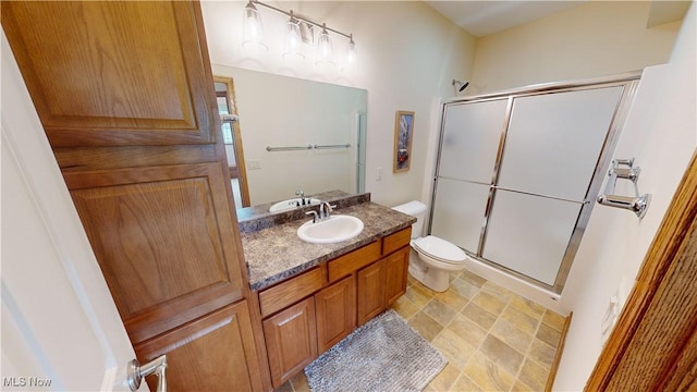 bathroom with vanity, toilet, and a shower with door