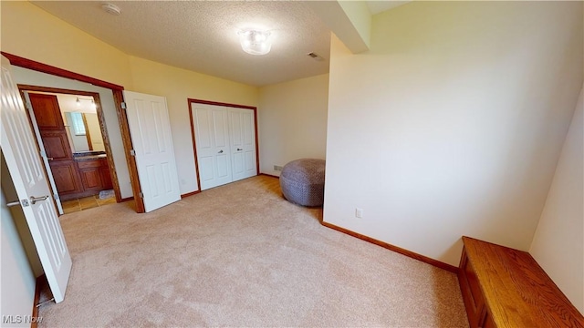 carpeted bedroom featuring ensuite bathroom, a textured ceiling, and a closet