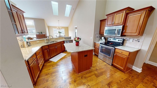 kitchen featuring a skylight, sink, a center island, pendant lighting, and appliances with stainless steel finishes