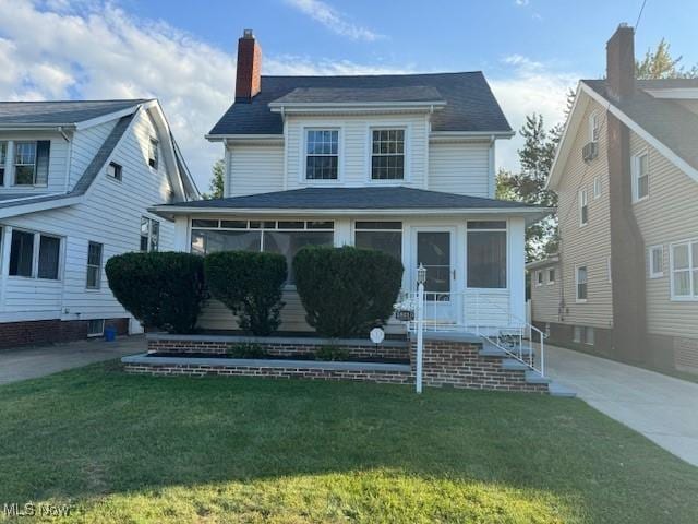 view of front of home with a sunroom and a front lawn