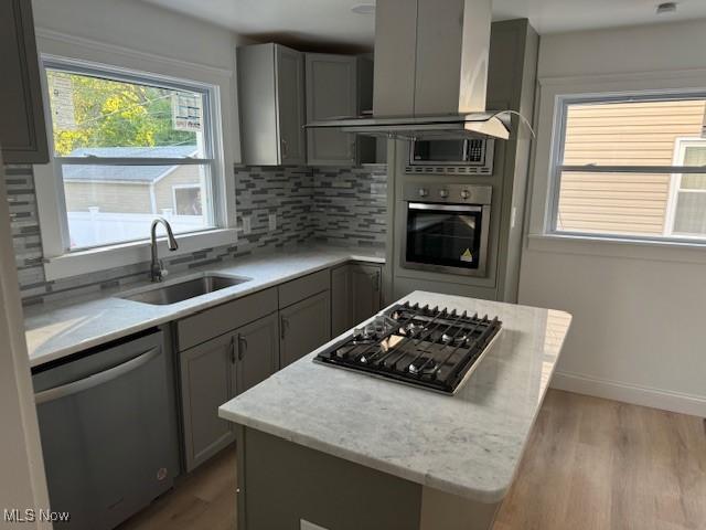 kitchen featuring sink, a center island, stainless steel appliances, and range hood