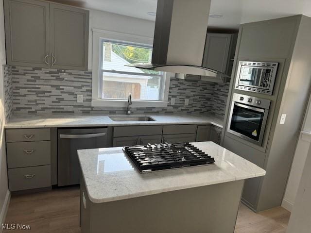 kitchen with a center island, island exhaust hood, sink, and appliances with stainless steel finishes