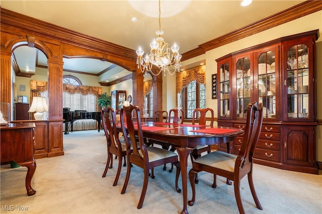 dining area featuring light carpet, a notable chandelier, arched walkways, and ornate columns