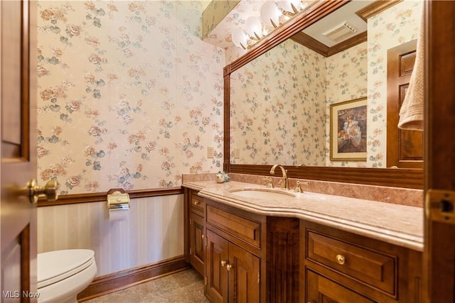 half bath featuring a wainscoted wall, visible vents, toilet, wallpapered walls, and vanity