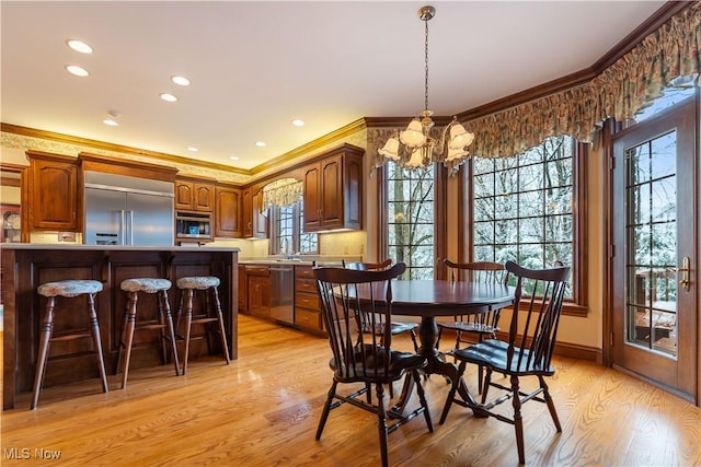 dining space featuring light wood finished floors, an inviting chandelier, crown molding, and a wealth of natural light