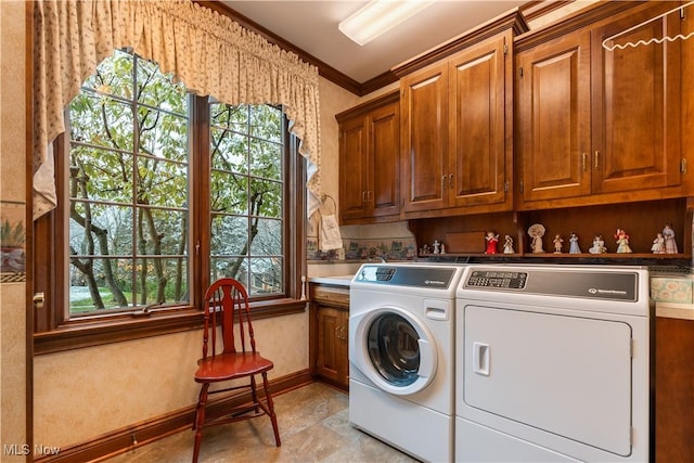 laundry room with washing machine and clothes dryer, cabinet space, crown molding, and a wealth of natural light