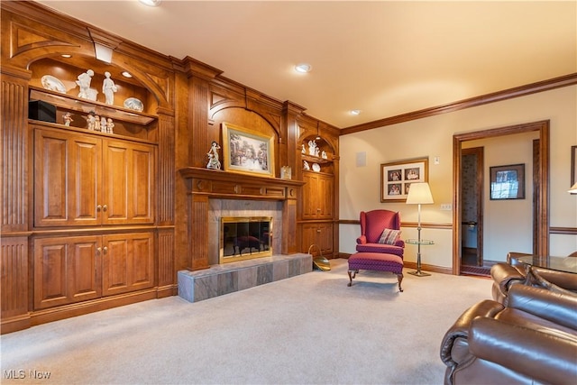 living area featuring a tiled fireplace, baseboards, crown molding, and carpet