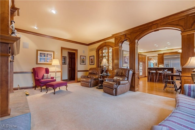 living area with light colored carpet, decorative columns, and ornamental molding