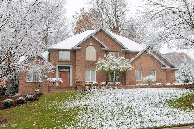 view of front of property featuring brick siding, a lawn, and a chimney