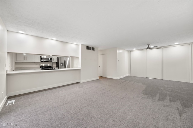 unfurnished living room with ceiling fan, carpet floors, and a textured ceiling