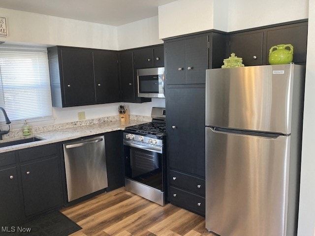 kitchen with stainless steel appliances, light hardwood / wood-style floors, and sink