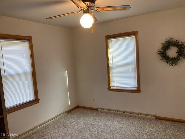 carpeted empty room featuring a baseboard radiator and ceiling fan