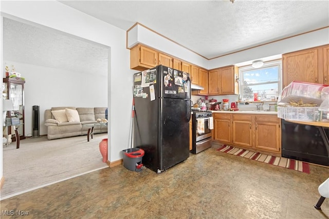 kitchen featuring sink, black fridge, a textured ceiling, and gas range