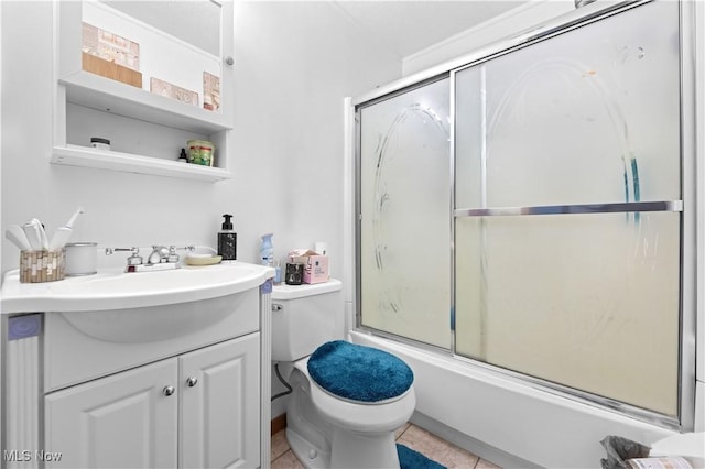 full bathroom with combined bath / shower with glass door, vanity, toilet, and tile patterned flooring