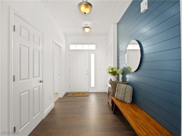 foyer with a textured ceiling, dark hardwood / wood-style flooring, and wood walls