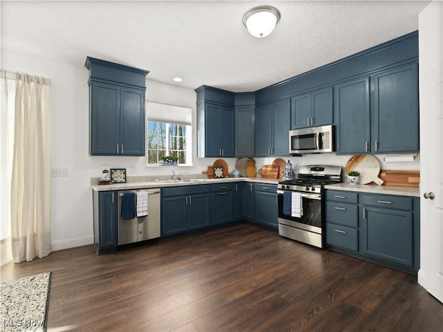 kitchen featuring blue cabinetry, appliances with stainless steel finishes, dark wood-type flooring, and sink