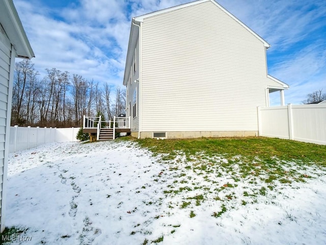 view of snowy exterior with a lawn and a wooden deck