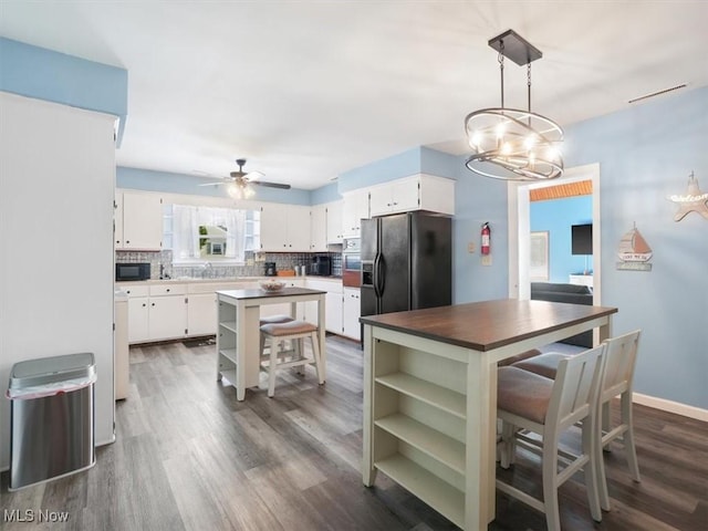 kitchen with black appliances, white cabinetry, a kitchen island, and pendant lighting