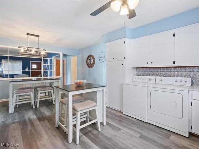 7630 Darling Ave, Conneaut, OH 44030 - clothes washing area with washer and dryer, wood finished floors, ceiling fan with notable chandelier, and cabinet space