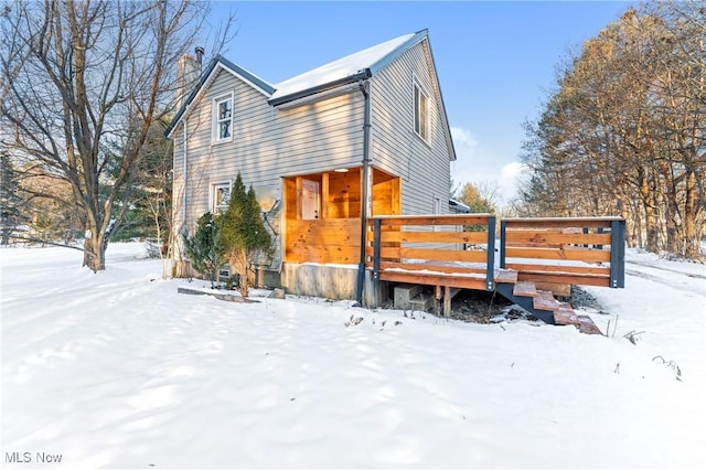 snow covered back of property with a wooden deck