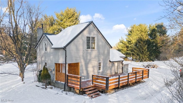 snow covered back of property with a deck