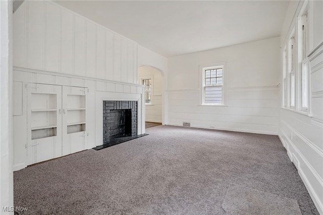 unfurnished living room with carpet flooring and a brick fireplace