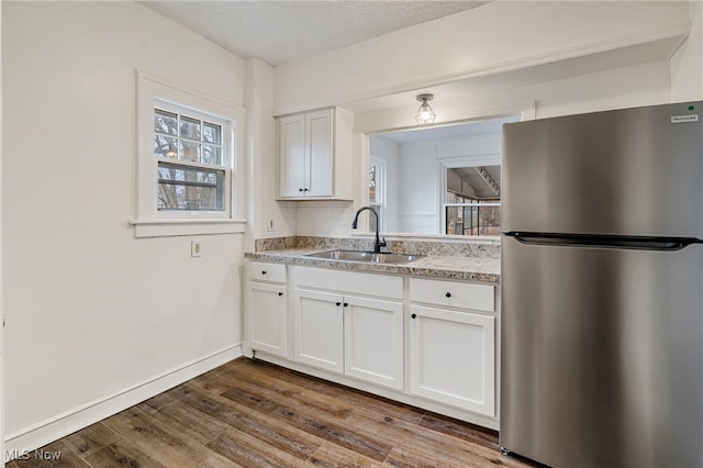 kitchen with stainless steel fridge, sink, white cabinets, and hardwood / wood-style flooring