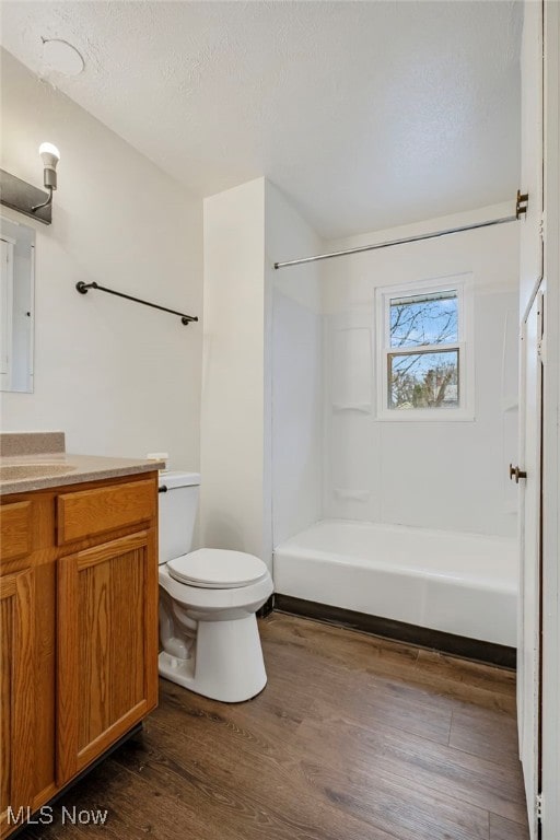 bathroom with hardwood / wood-style flooring, vanity, toilet, and a textured ceiling